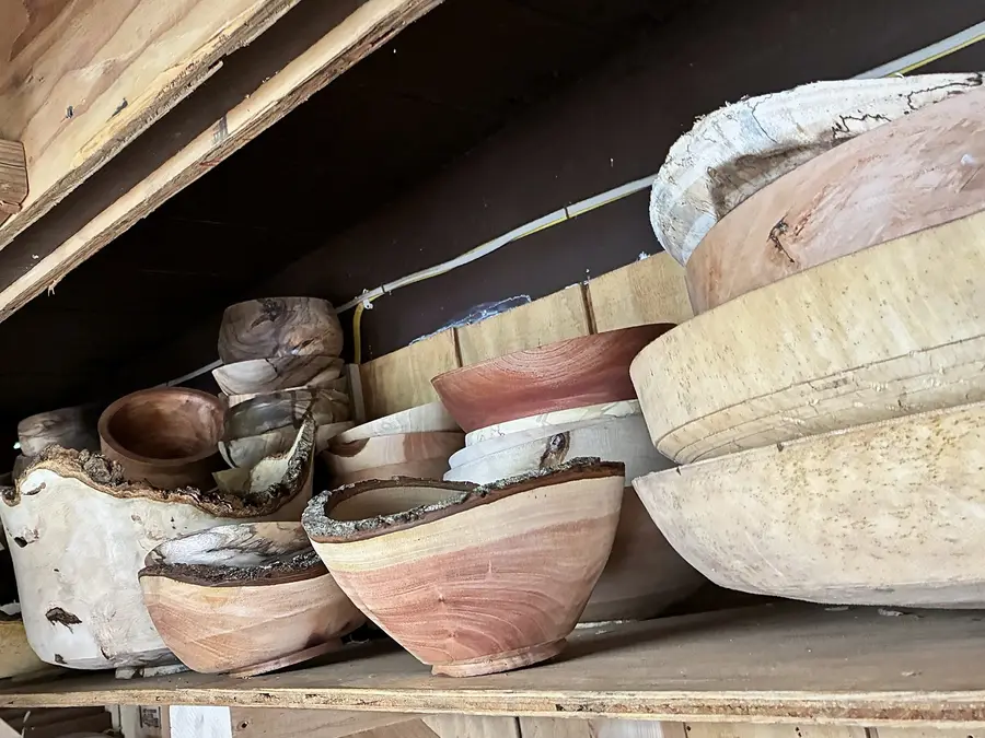 Bowls on a high shelf in the shop, some roughed out thick and some with the bark left on the rim