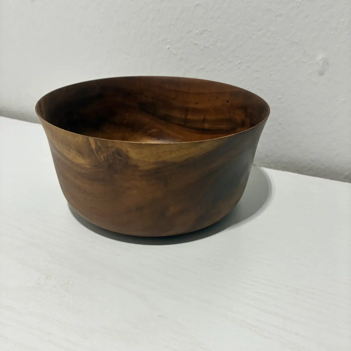Kaleb’s flared bowl, deep, its rim opening outward and dark streaks in the grain