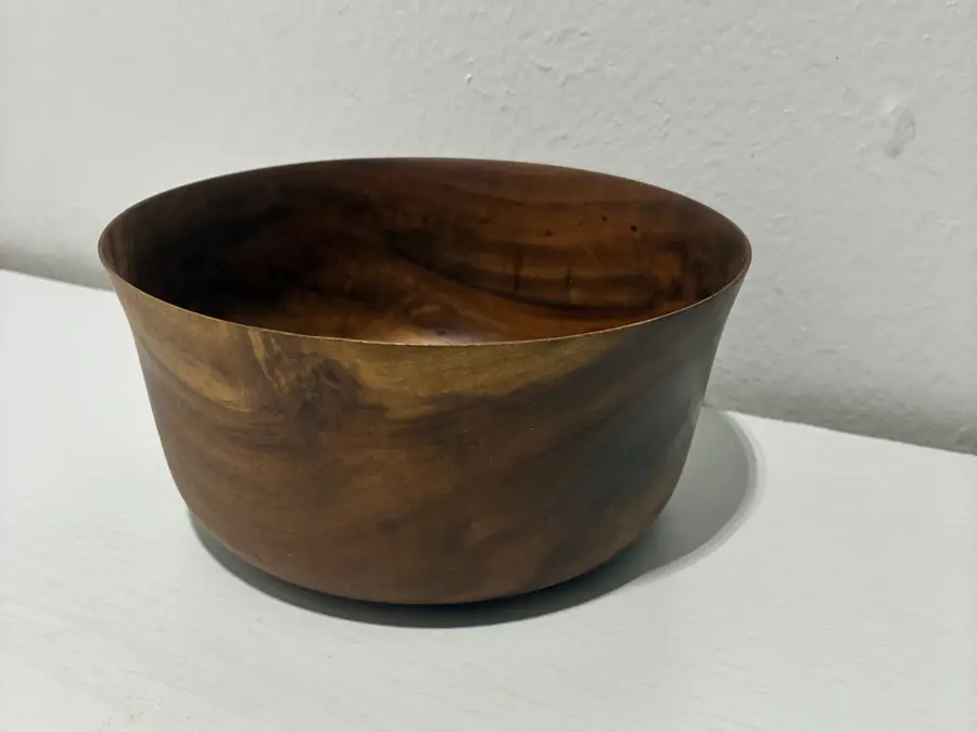 Kaleb’s flared bowl, deep, its rim opening outward and dark streaks in the grain