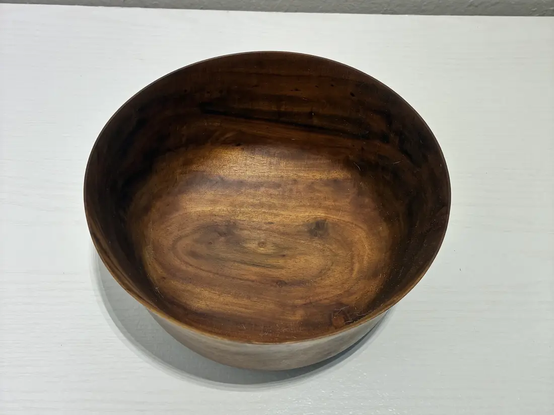 Looking down into the flared bowl, its oiled grain swirling dark and gold
