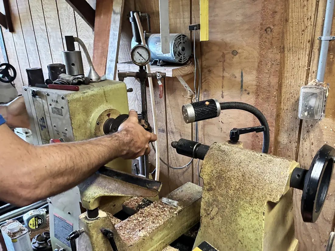 Kaleb’s hand on the chuck of his lathe, the tool rest and tailstock beside it