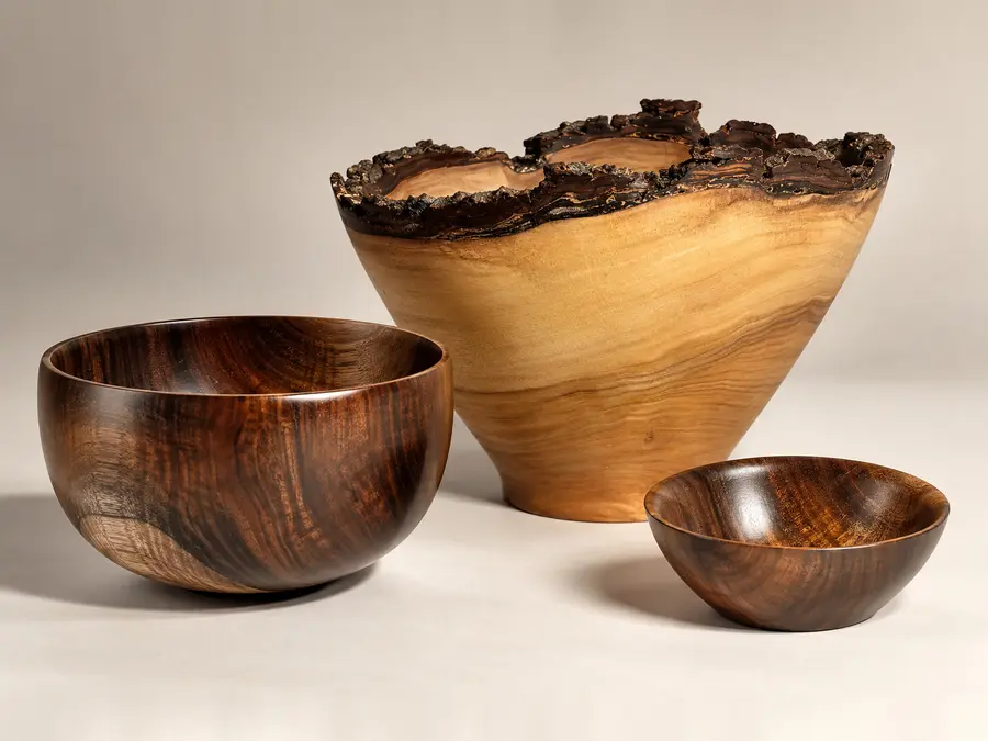 Kaleb’s curly koa pair, a deep bowl and a small one, in front of his natural-edge naio bowl with its bark rim