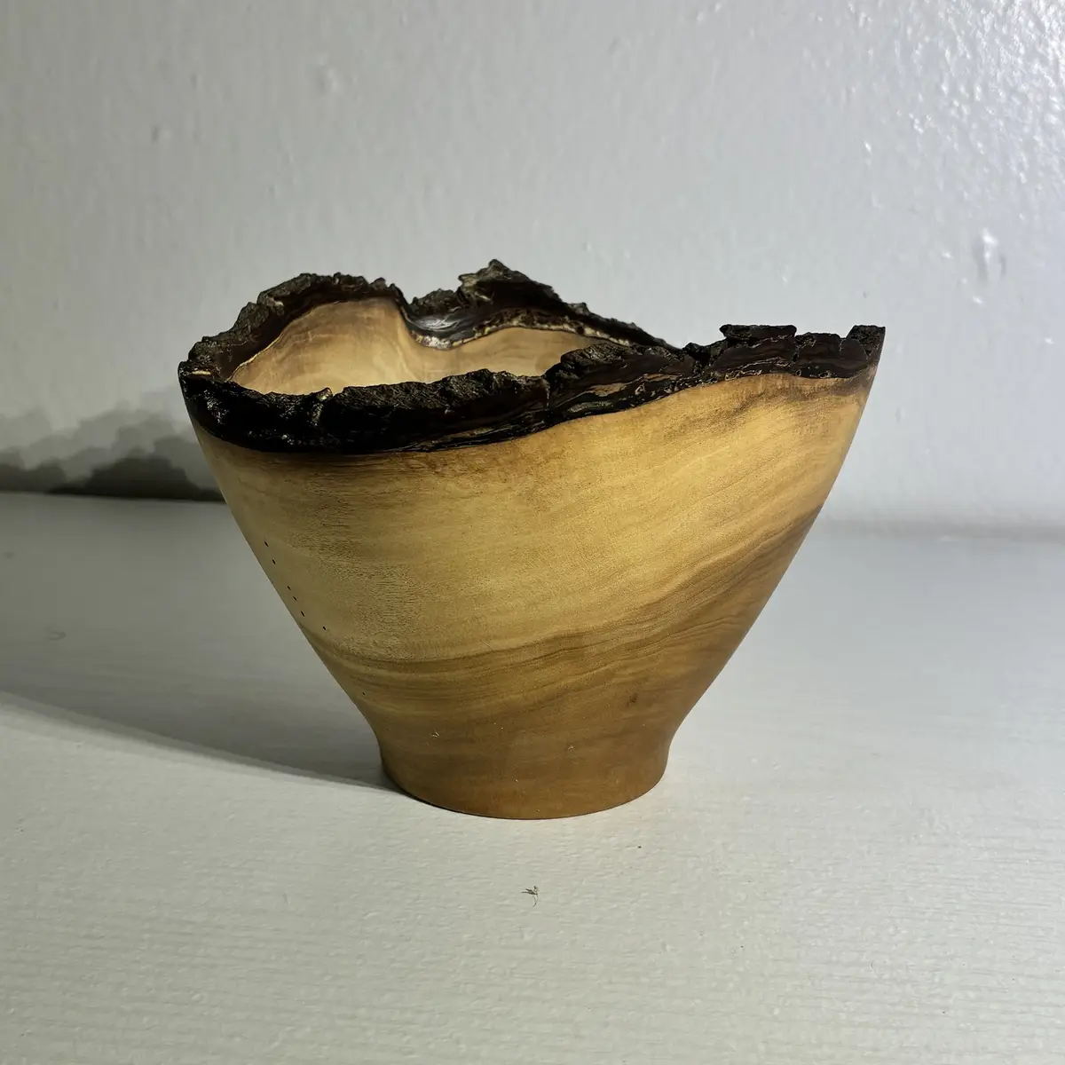 Kaleb’s natural-edge naio bowl: pale, fine-grained wood with the tree’s dark bark left on as its wavy rim