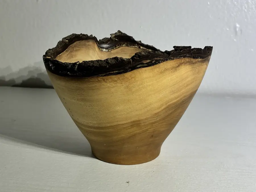 Kaleb’s natural-edge naio bowl: pale, fine-grained wood with the tree’s dark bark left on as its wavy rim