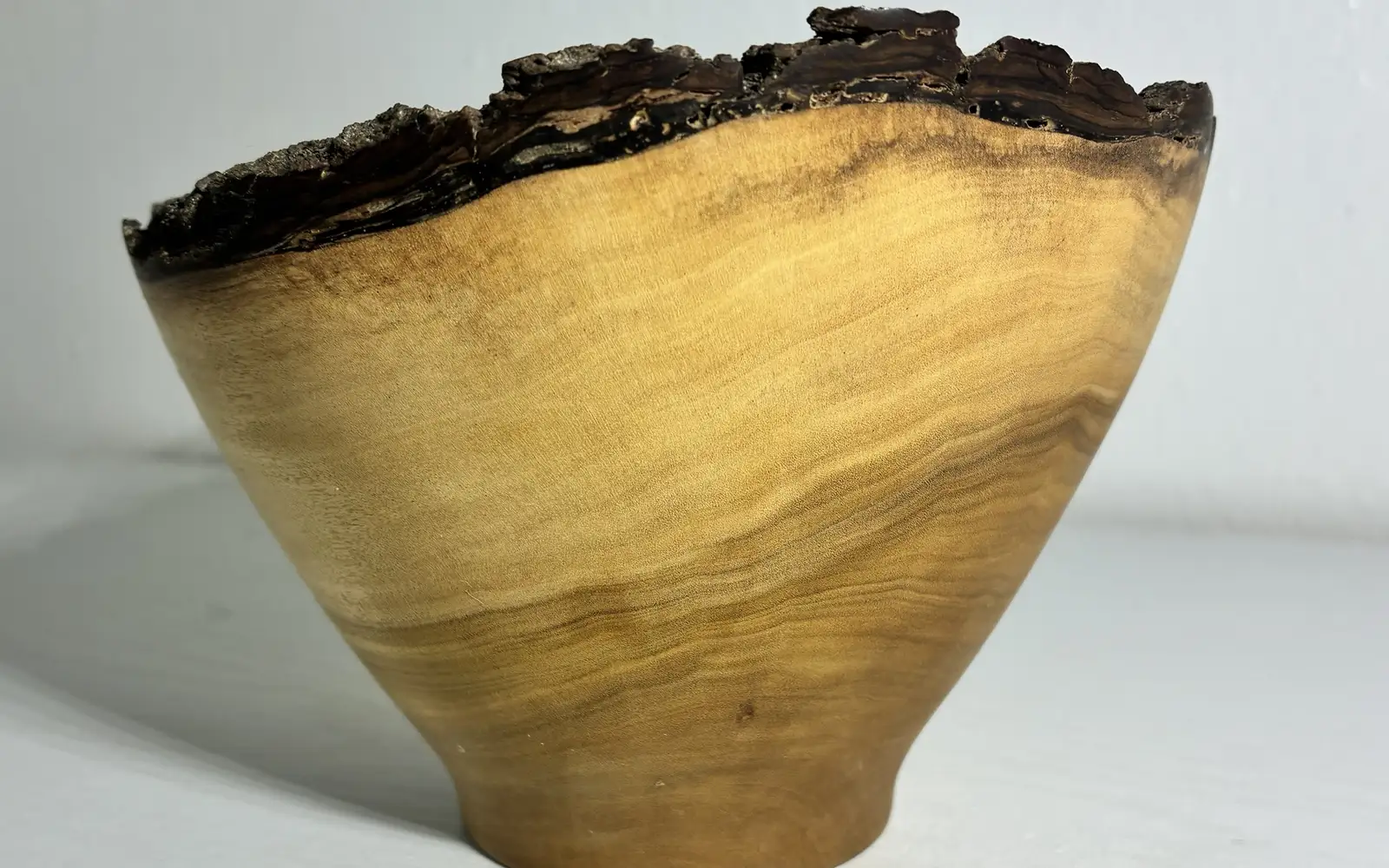 Kaleb’s natural-edge naio bowl close up: golden grain under a rim of dark bark