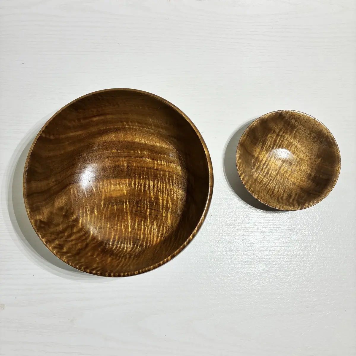 The curly koa pair from above, the curl catching the light across both bowls