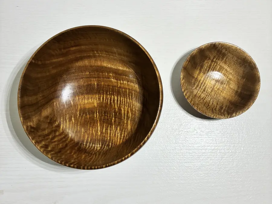 The curly koa pair from above, the curl catching the light across both bowls