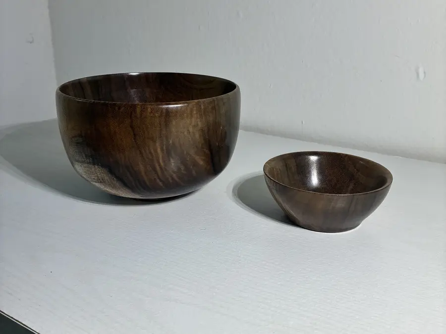 The curly koa pair from a low angle, the larger bowl’s figure running up its side