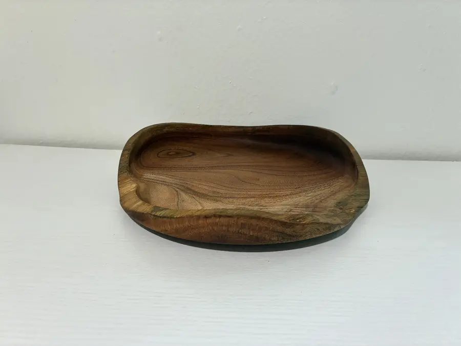 Kaleb’s free-form platter on a white shelf, its grain circling a knot near one edge