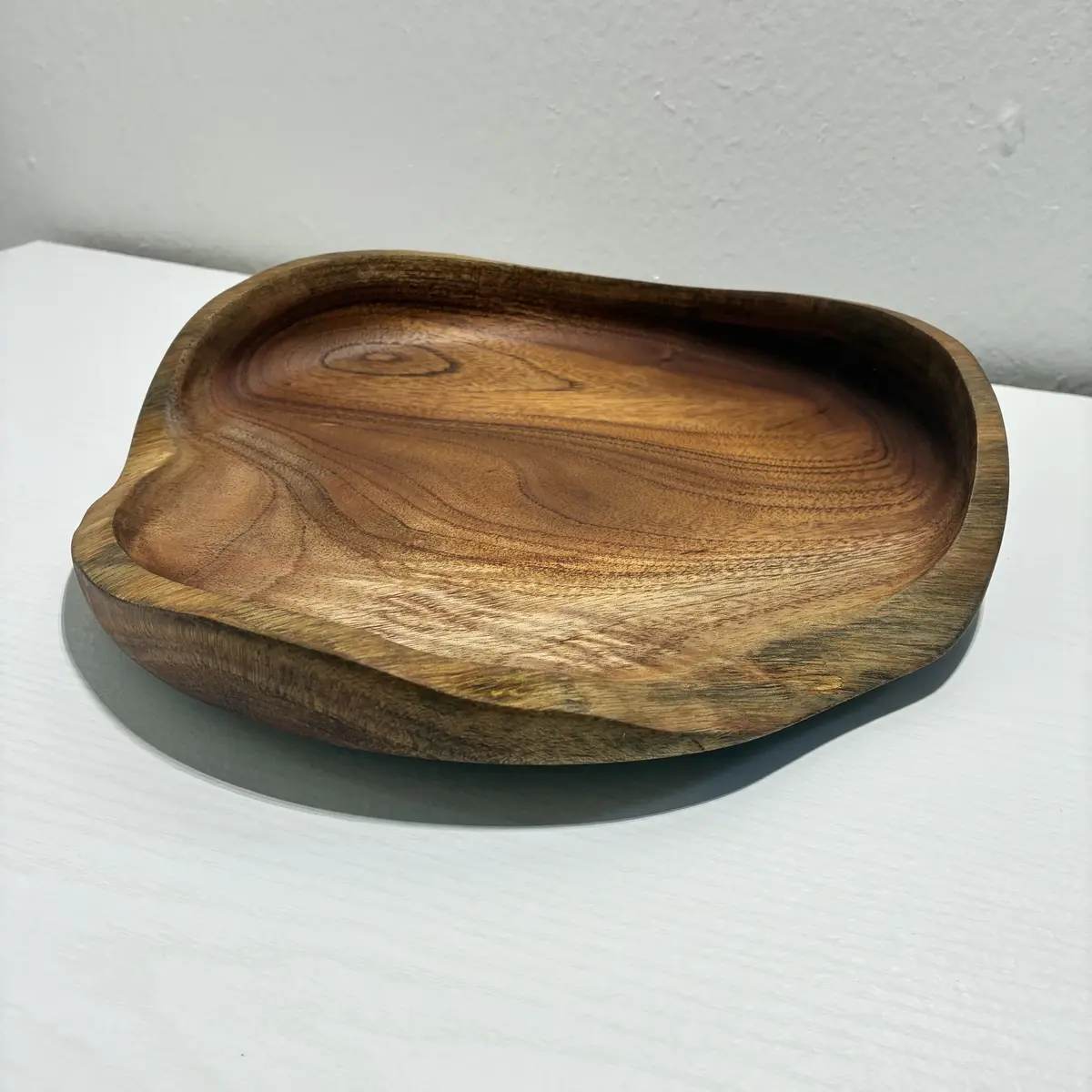 Kaleb’s free-form platter at an angle, its rim rising and falling with the wood