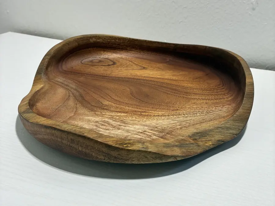 Kaleb’s free-form platter at an angle, its rim rising and falling with the wood