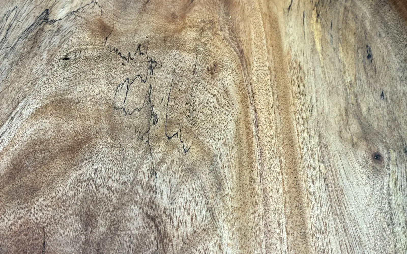Close in on the spalted mango bowl: black zone lines wandering through pale grain