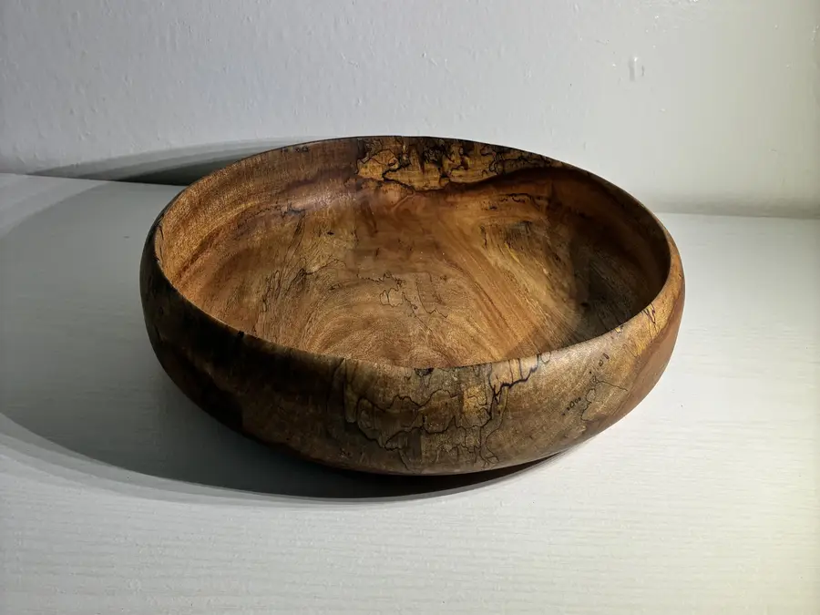 The spalted mango bowl in raking light, casting a long shadow