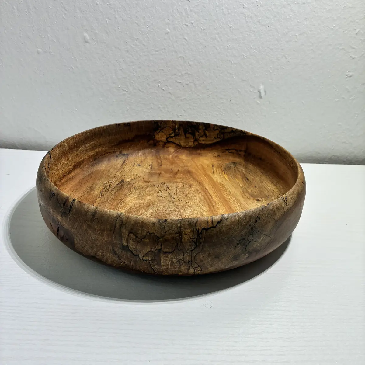 Kaleb’s spalted mango bowl, low and wide, with black spalting lines across its side